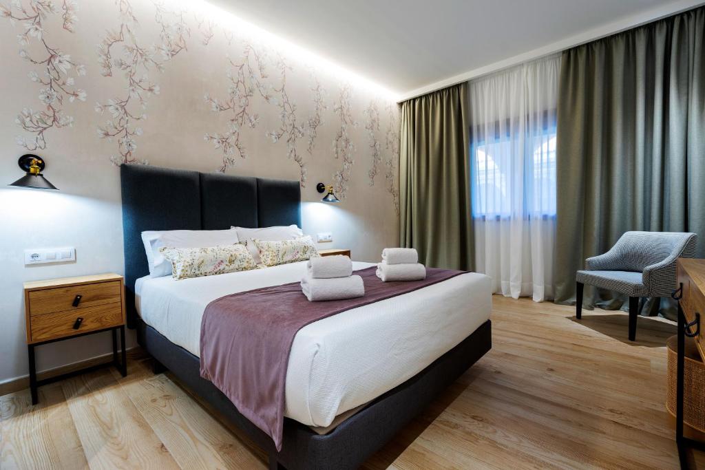 um quarto com uma cama grande e uma cadeira em Complejo Valle Grande em Zarza la Mayor