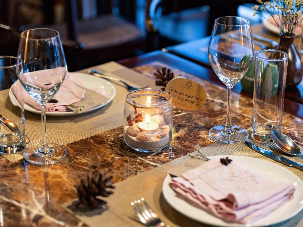 a table with glasses and plates of food and candles at Hera Grand Luxury Cruise in Ha Long