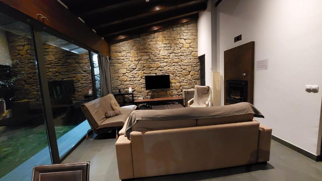 sala de estar con sofá y pared de piedra en Alojamientos Marel Sanabria, en Villarino de Sanabria