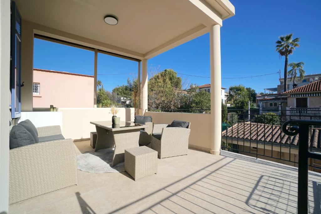 Elle comprend une terrasse dotée d'un mobilier blanc et de grandes fenêtres. dans l'établissement Magnifique haut de villa chez Charlotte, à Antibes