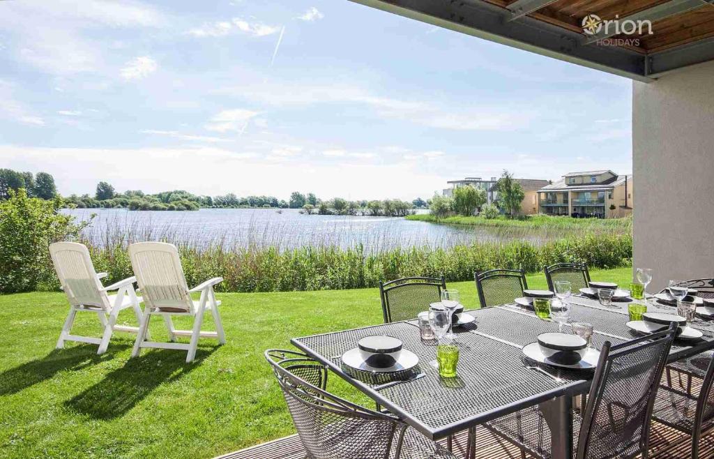 a patio with a table and chairs and a view of a lake at Clearwater 28, Wild Briar - P in Somerford Keynes