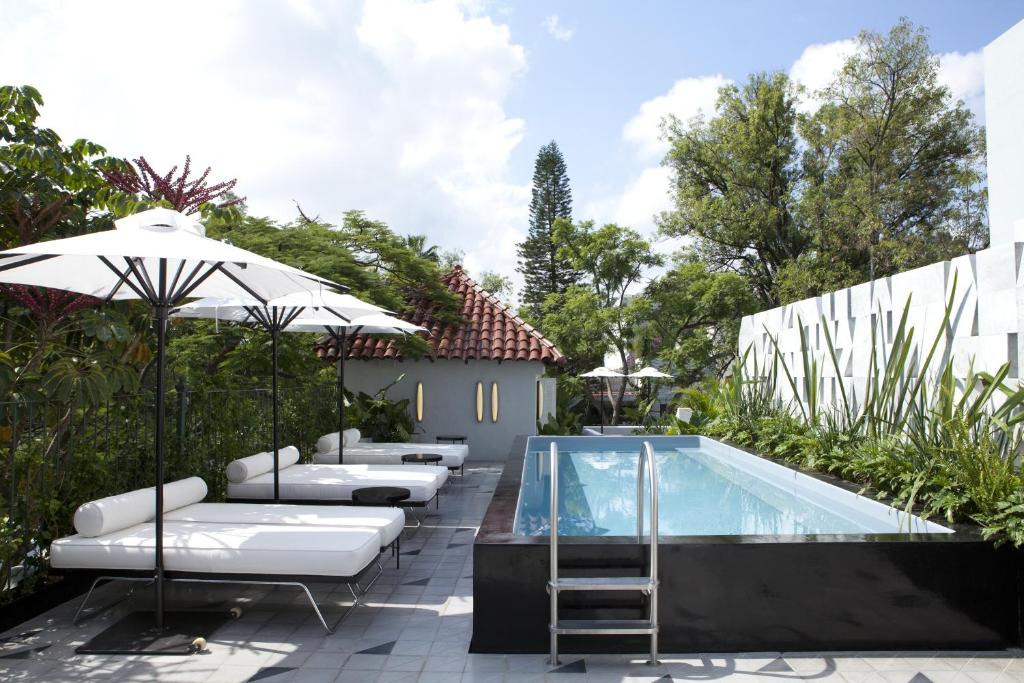 a pool with chaise lounge chairs and an umbrella at Casa Habita, a Member of Design Hotels in Guadalajara