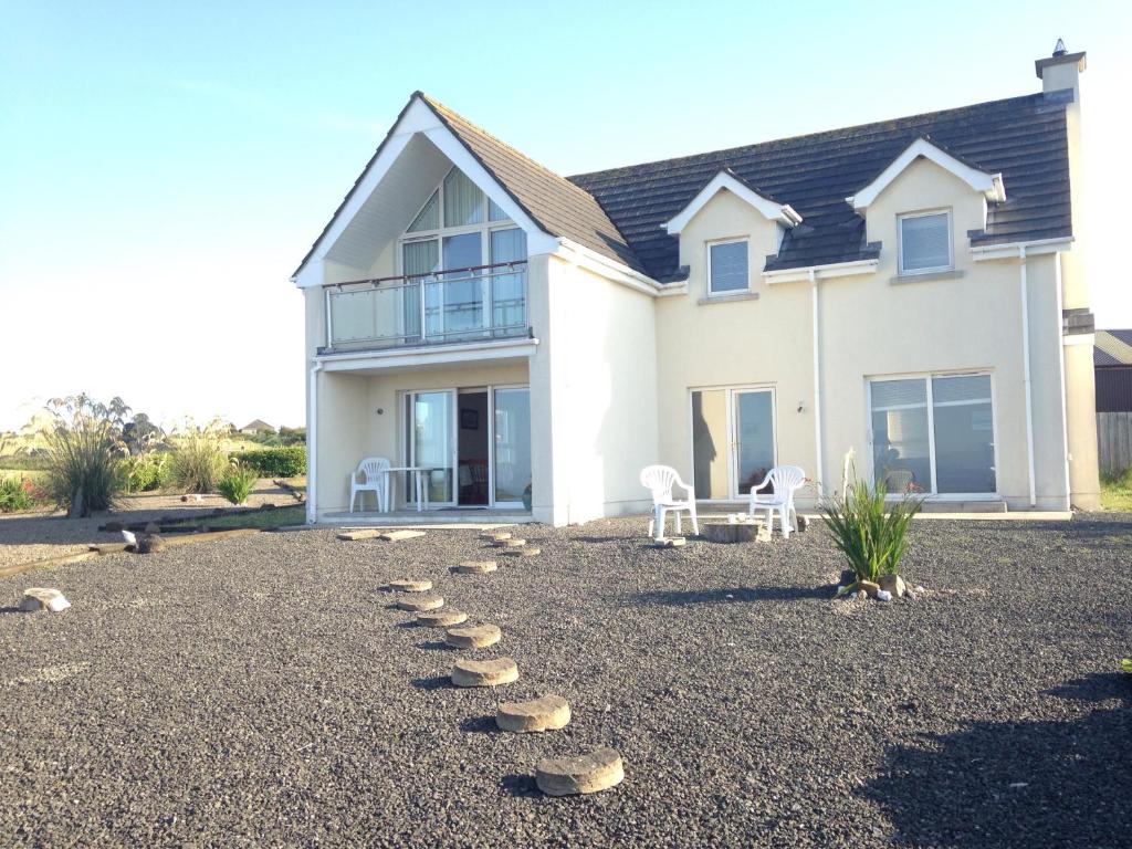 a house with rocks on the ground in front of it at Stunning Detached 3 Bedroom House Islandandmagee in Larne