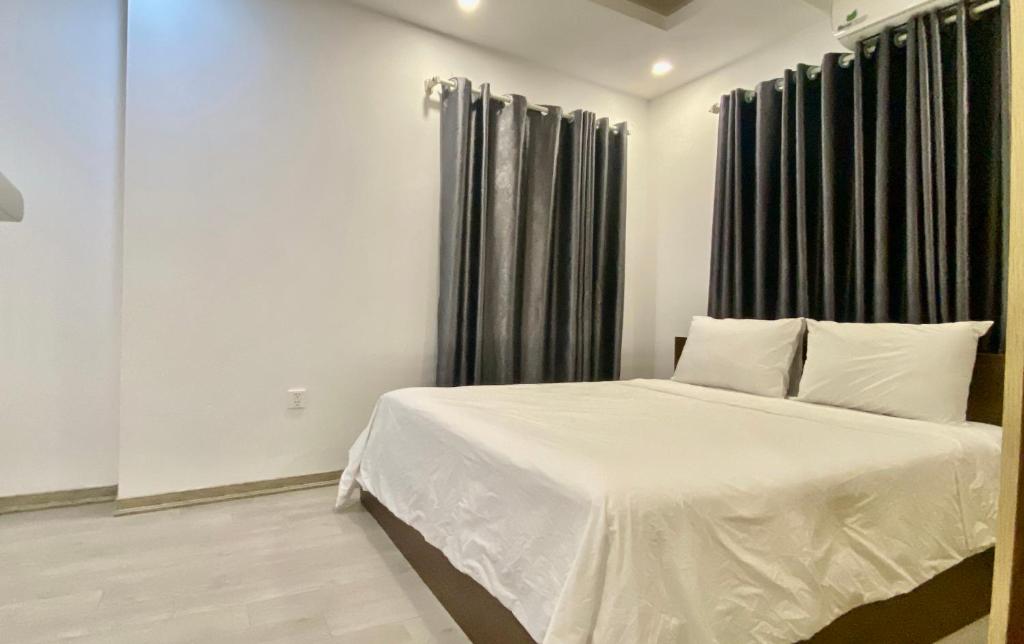 a bedroom with a white bed with black curtains at Wins Apartment in Hanoi