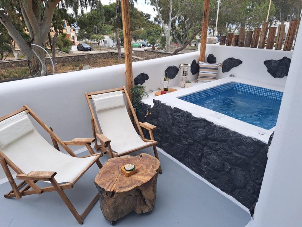 two chairs and a swimming pool on the deck of a house at Asera Suites only 300m from Kamari Beach in Kamari