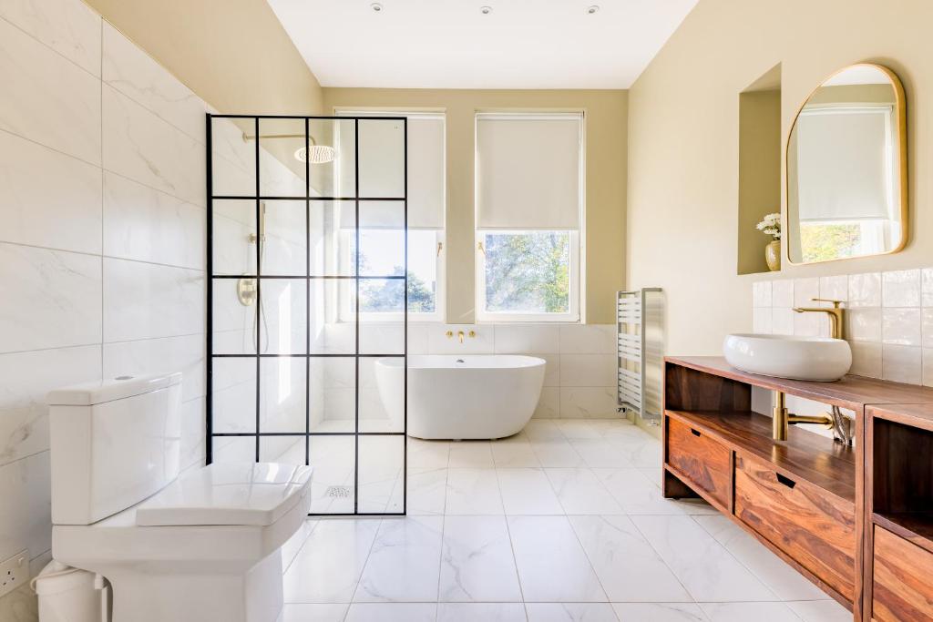 a bathroom with a tub and a toilet and a sink at Beautiful large luxury home in London in Sidcup