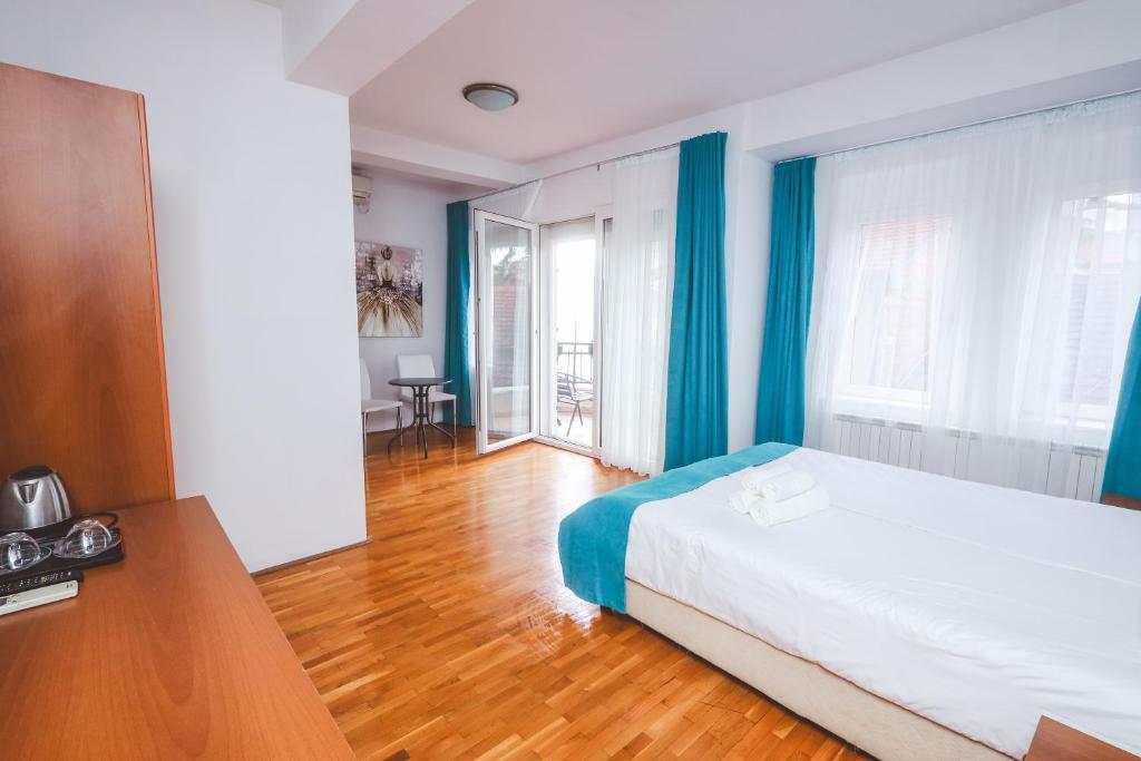 Schlafzimmer mit einem Bett mit blauen Vorhängen und Holzboden in der Unterkunft AMMOTTI Hotel and Apartments in Ohrid