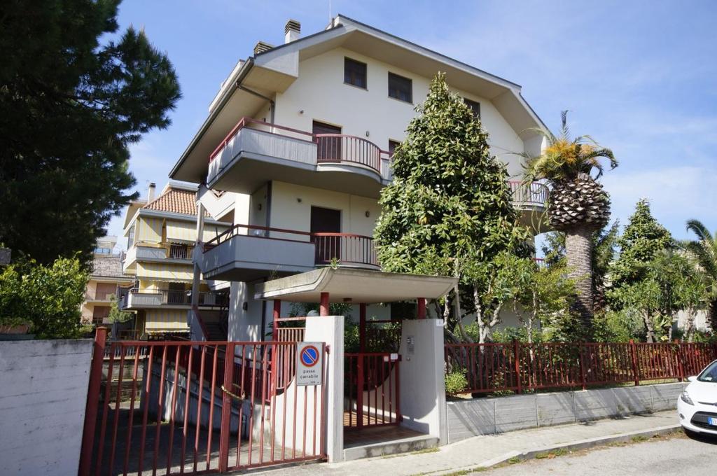 a white house with a fence and a tree at Palazzina Magnolia in San Benedetto del Tronto