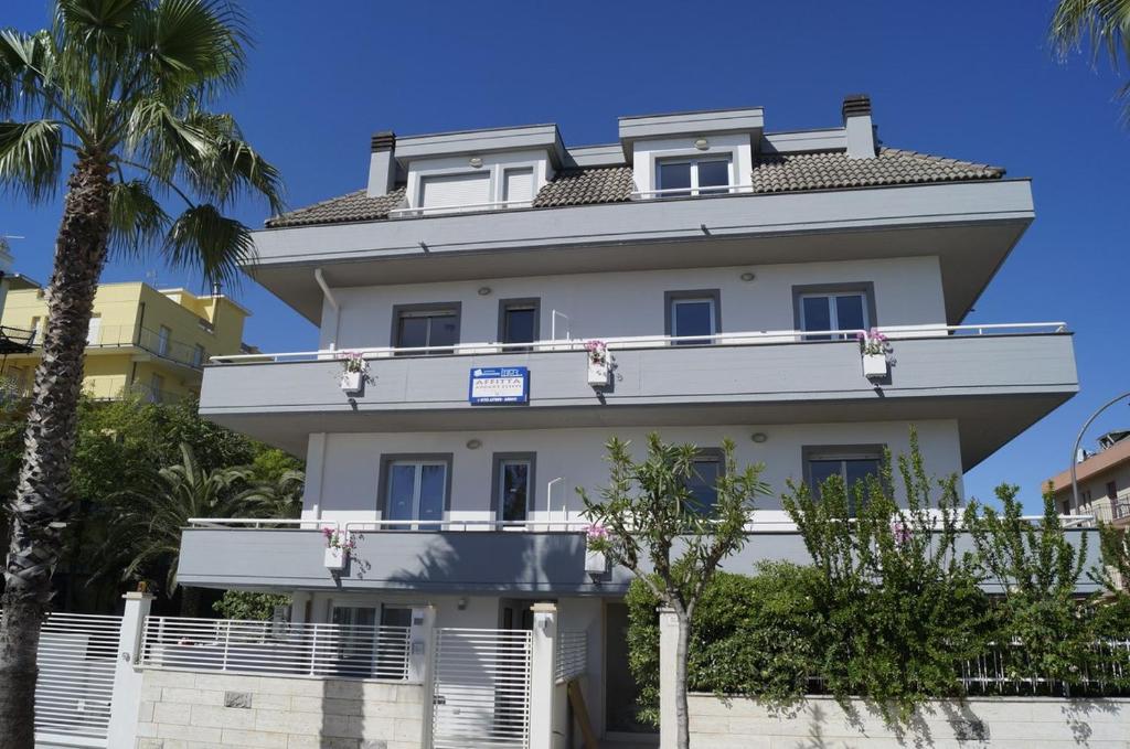 a large white building with trees in front of it at Palazzina Cala Luna in San Benedetto del Tronto