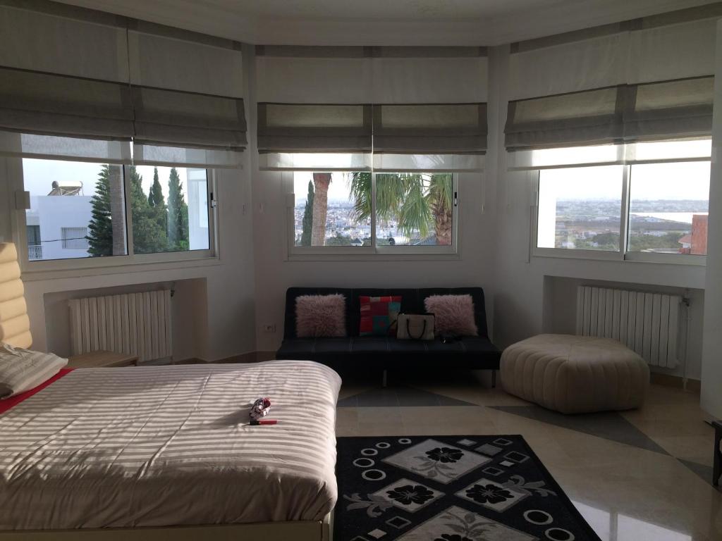迦玛特Villa Gammarth - Suite N1 Bis的一间卧室配有一张床、一张沙发和窗户。