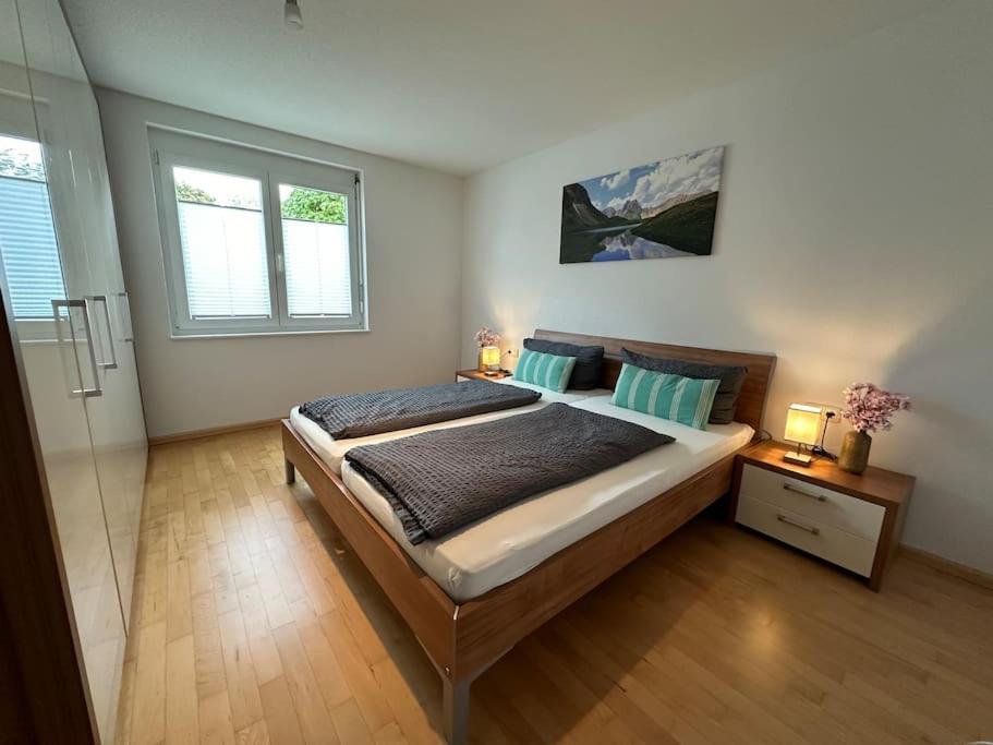 een slaapkamer met een groot bed en 2 ramen bij Ferienwohnung Bodenseeblick in Hagnau