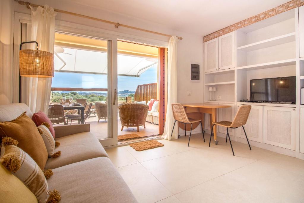 een woonkamer met een bank en een tafel bij Portisco Bouganville Seaside Charm Flat W/ Veranda in Marina di Portisco