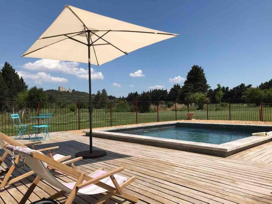 an umbrella sitting on a deck next to a pool at Loft en campagne proche de l’Isle sur Sorgue in Le Thor