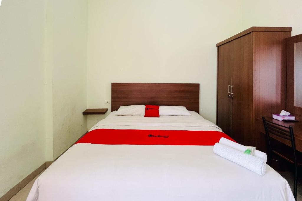 een slaapkamer met een groot wit bed en een rode deken bij RedDoorz At Teratai Homestay Medan Amplas in Medan