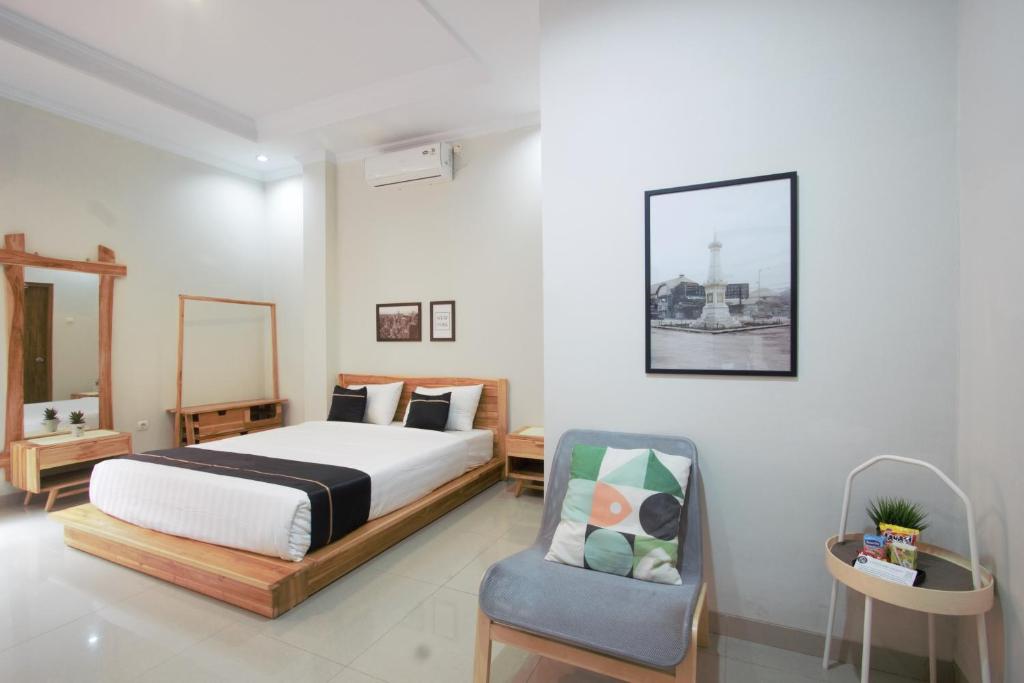 een slaapkamer met een bed en een stoel bij Cendhani Raras Residence in Demangan