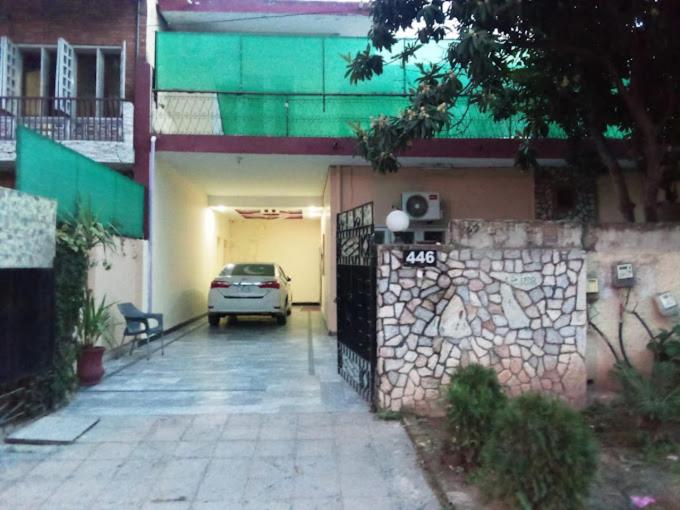une voiture garée dans un garage à côté d'un bâtiment dans l'établissement Rose Lodges Guest House, à Islamabad