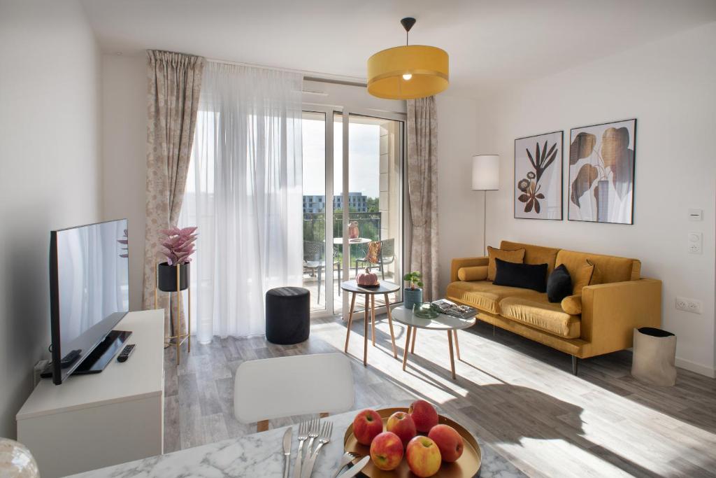 a living room with a couch and a table with a bowl of fruit at DOMITYS SARIA in Serris