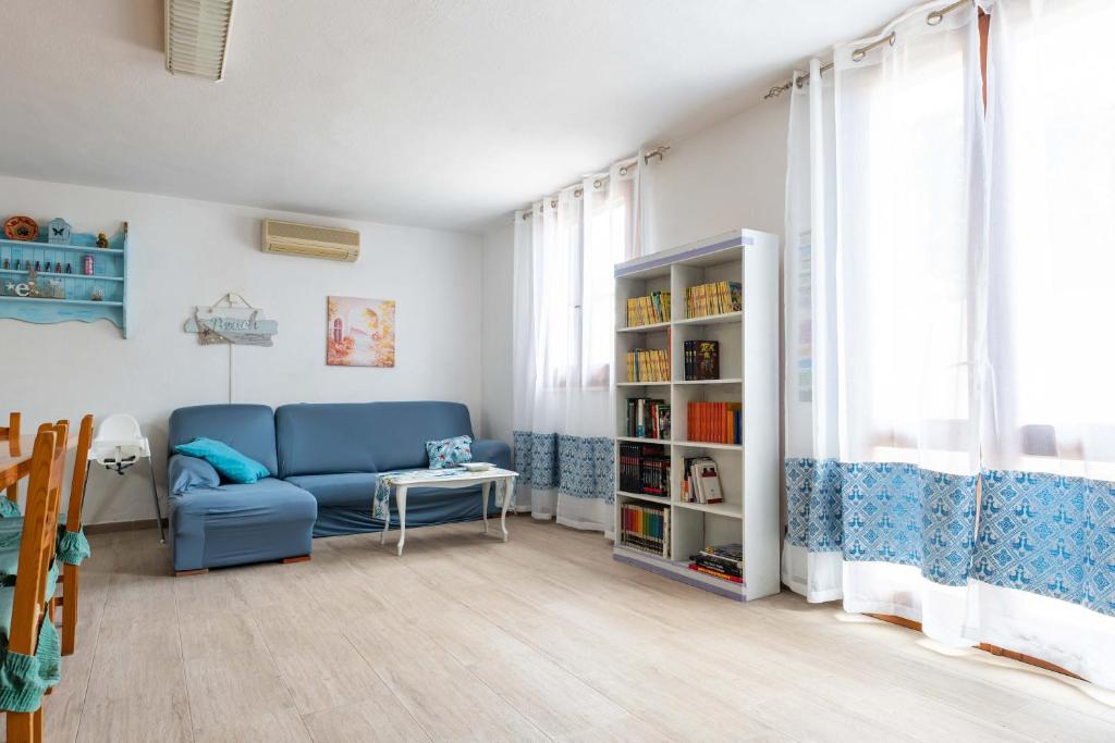 een woonkamer met een blauwe bank en een boekenplank bij Elena’s Maison in Solanas