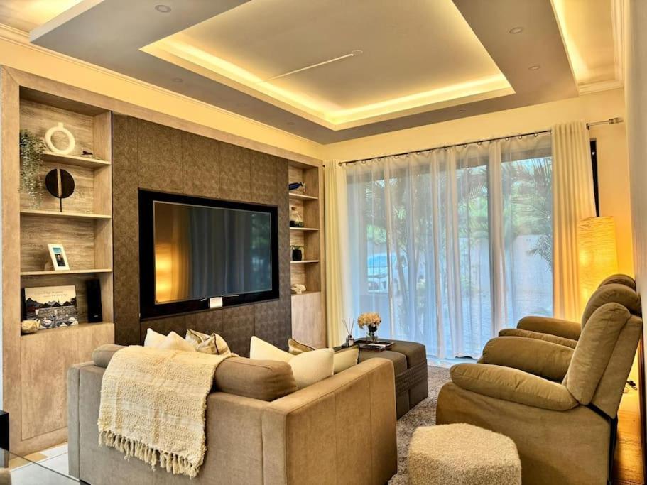 a living room with a couch and a tv at Charming 3 bedroom apartment with swimming pool in Flic-en-Flac