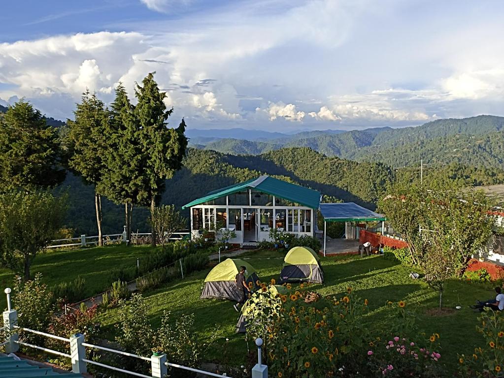 a view of a house with tents in a field at Chirping Orchard, Mukteshwar in Mukteswar