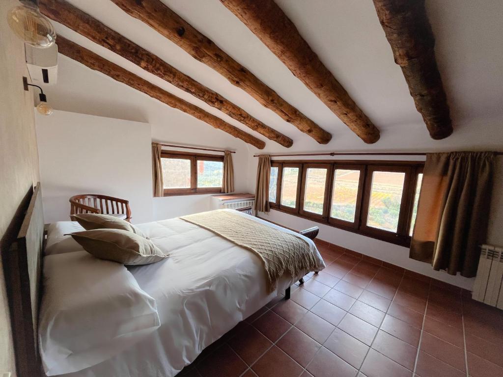 Schlafzimmer mit einem Bett mit weißer Bettwäsche und Fenstern in der Unterkunft Casa Rural Cal Vellet del Priorat in La Vilella Baixa