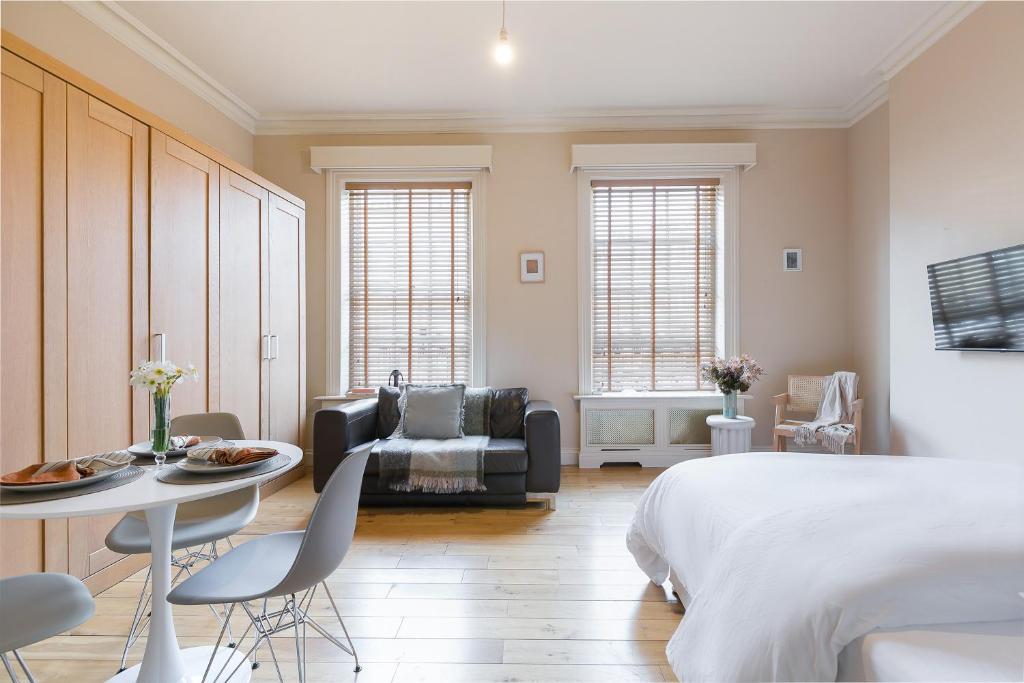 a bedroom with a bed and a table and a couch at Small sun lit studio minutes from Kings Cross station in London