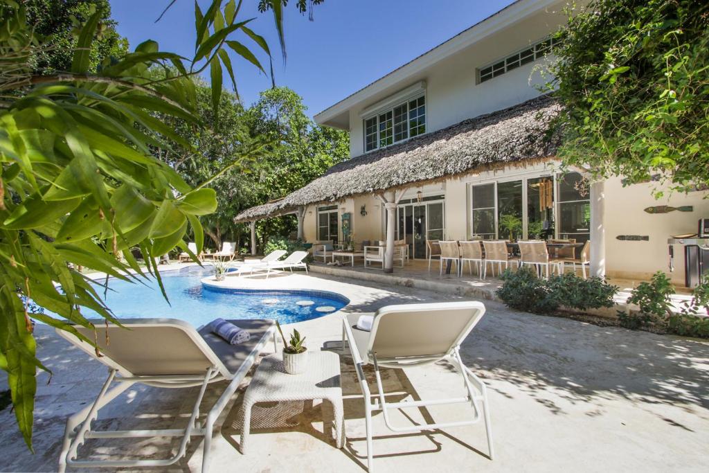 プンタ・カナにある5-Bedroom Pool Villa for up to 10 people in Puntacana Resort & Clubのプールと椅子が前にある家