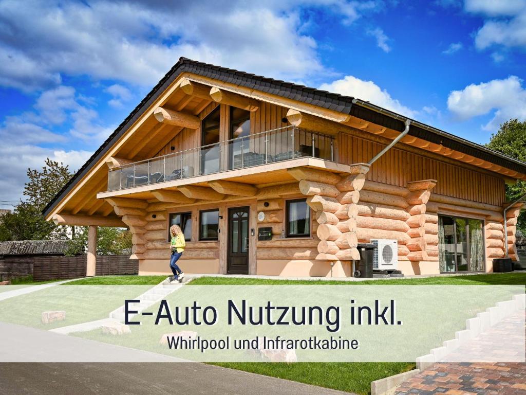 a person walking in front of a log house at Natur-Chalet zum Nationalpark Franz inkl. E-Auto in Allenbach