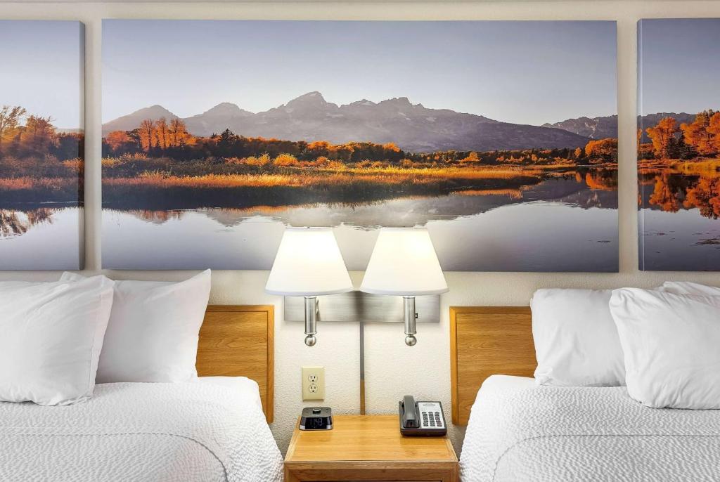 a hotel room with two beds and a painting of a lake at Days Inn by Wyndham Great Falls in Great Falls