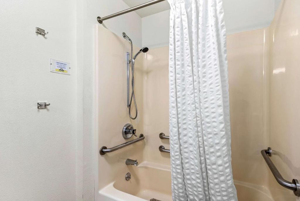 a bathroom with a shower with a white shower curtain at Days Inn by Wyndham Great Falls in Great Falls