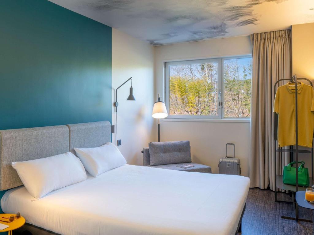 a bedroom with a large white bed and a chair at Ibis Barcelona Aeropuerto Viladecans in Viladecáns