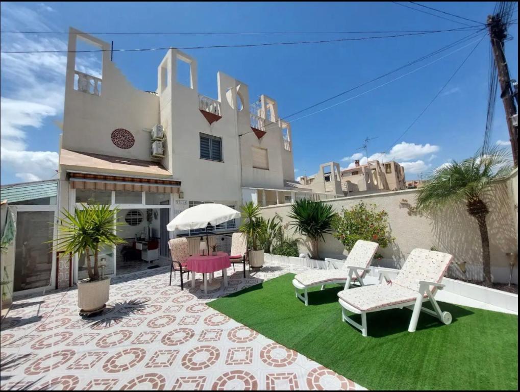 a patio with chairs and a lawn in front of a building at R-15 Rincón del Sol in Torrevieja