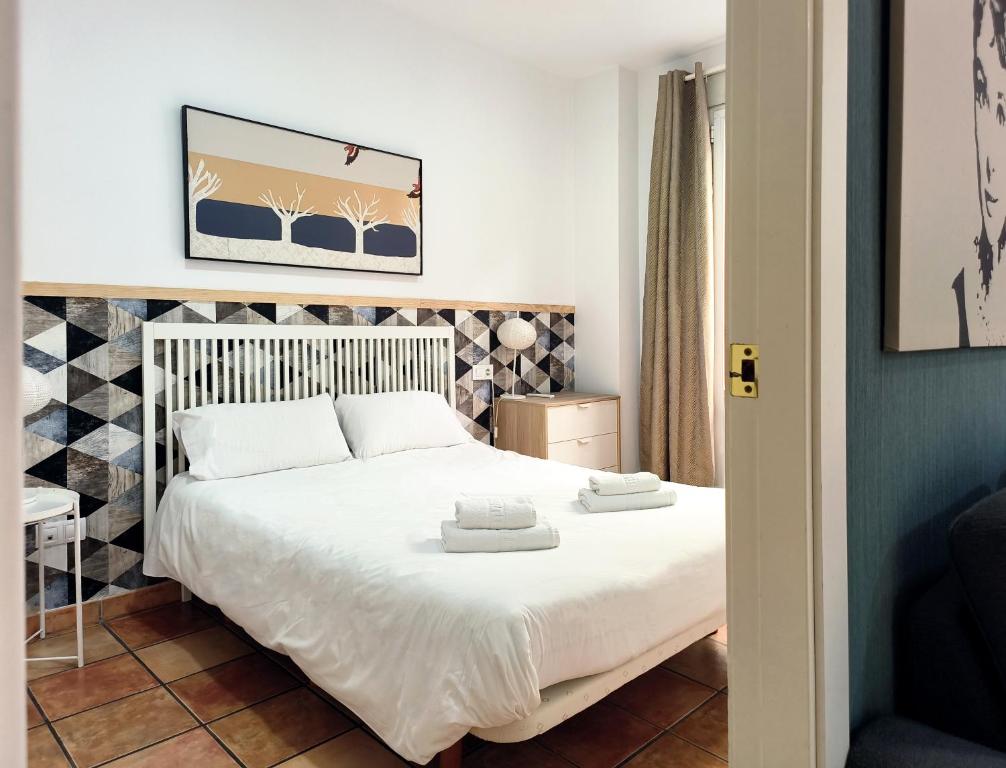 una camera da letto con un letto con due asciugamani sopra di Flats Friends Nave a Valencia