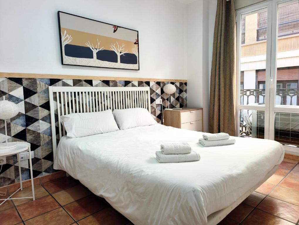 una camera da letto con un grande letto bianco con due asciugamani di Flats Friends Nave a Valencia