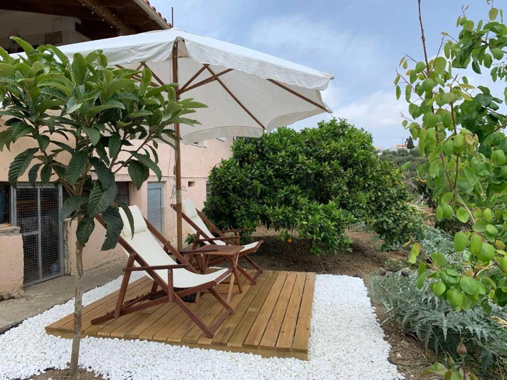 a couple of chairs and an umbrella on a wooden deck at The Garden House, Sitia in Sitia
