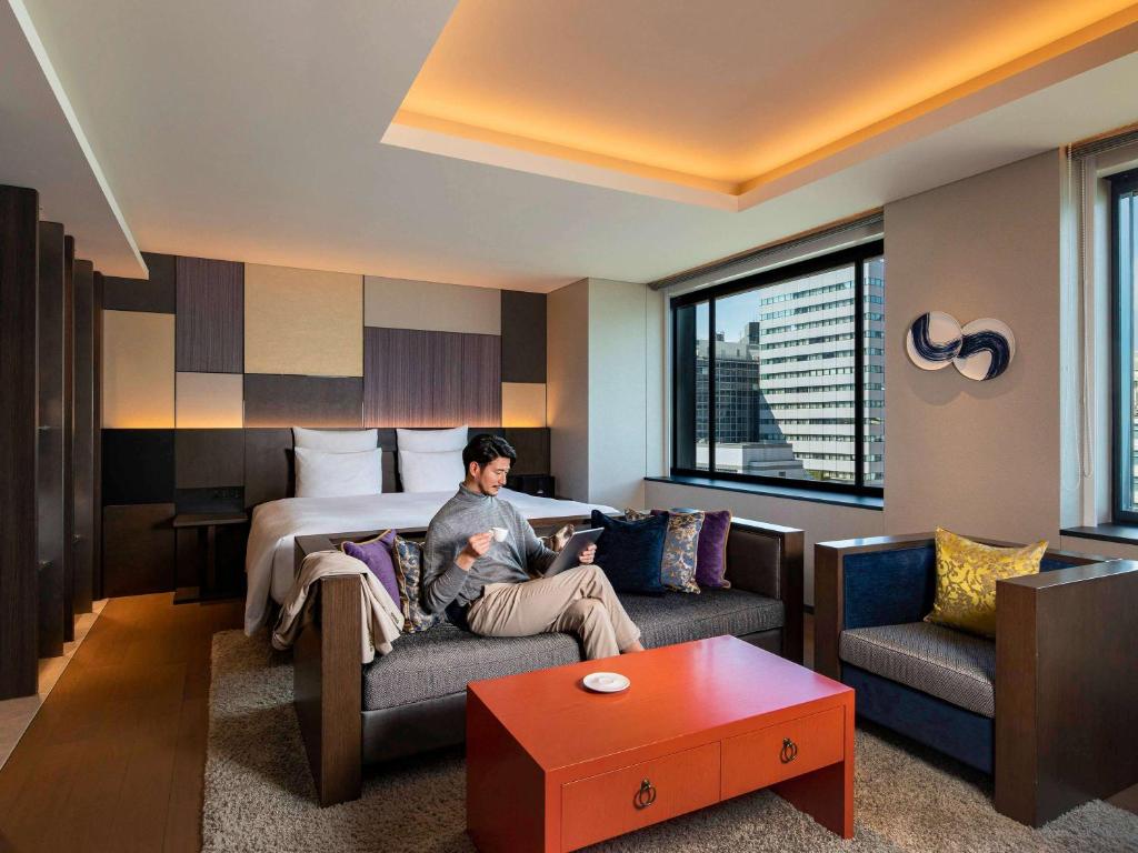 a woman sitting on a couch in a hotel room at Pullman Tokyo Tamachi in Tokyo