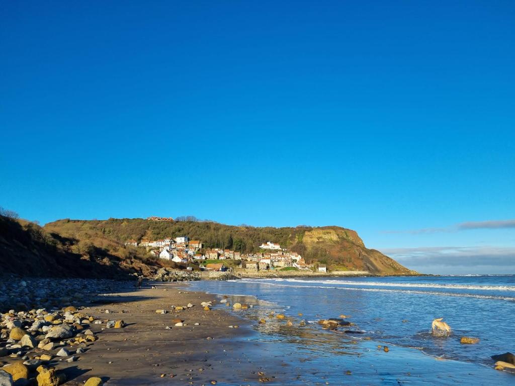 a view of a beach with houses on a hill at Cosy Cottage in Hinderwell, near Staithes & Whitby - Pet Friendly - 2nts min stay in Hinderwell