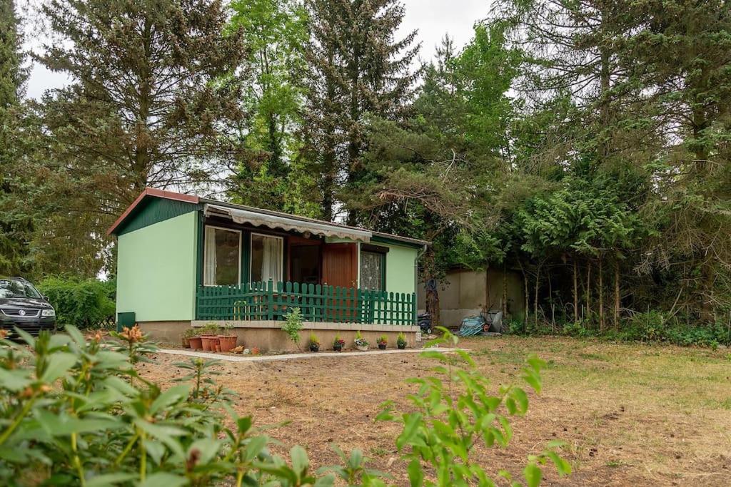 une petite maison verte avec une terrasse couverte dans une cour dans l'établissement Lovely summerhouse 40km from berlin!, à Biesenthal