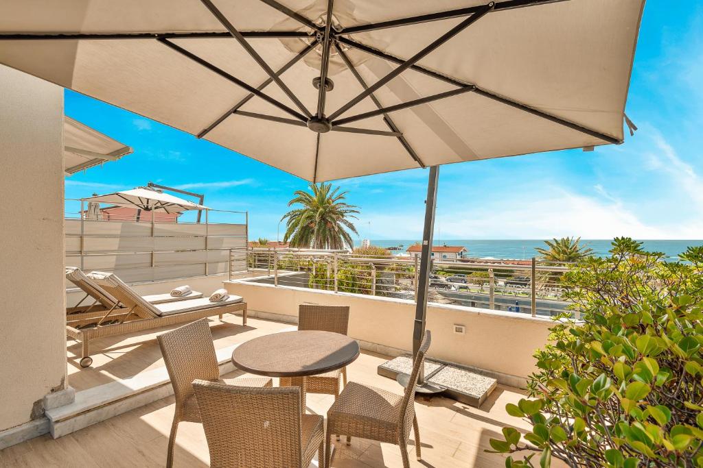 a patio with a table and chairs and an umbrella at Hotel Excelsior in Marina di Massa