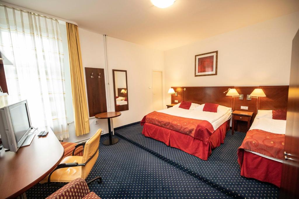 Habitación de hotel con 2 camas y escritorio en Hotel Grand en Řevnice