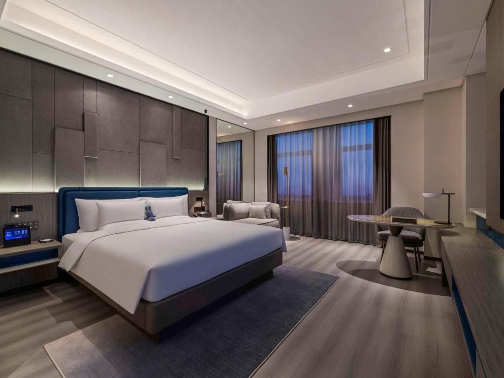 a bedroom with a large bed and a table at Novotel Kunshan Yangcheng Lake in Kunshan