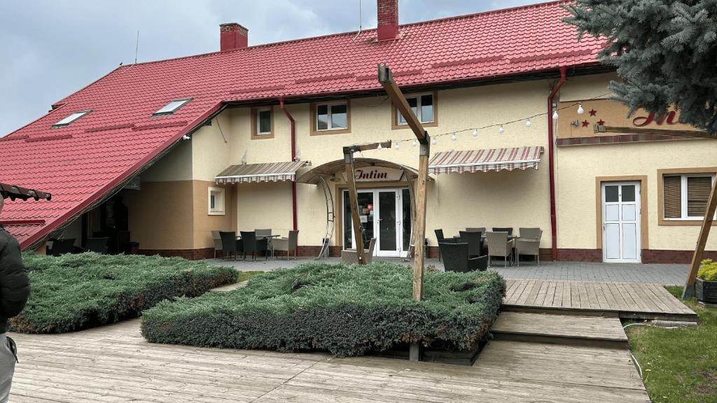 un edificio con techo rojo y terraza de madera en Hotel Intim en Rădăuţi