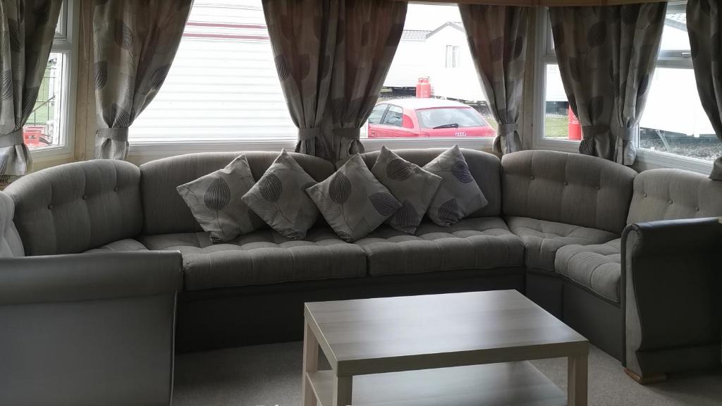 uma sala de estar com um sofá com almofadas e uma mesa em 3-Bed 8 berth static caravan in ingoldmells em Skegness
