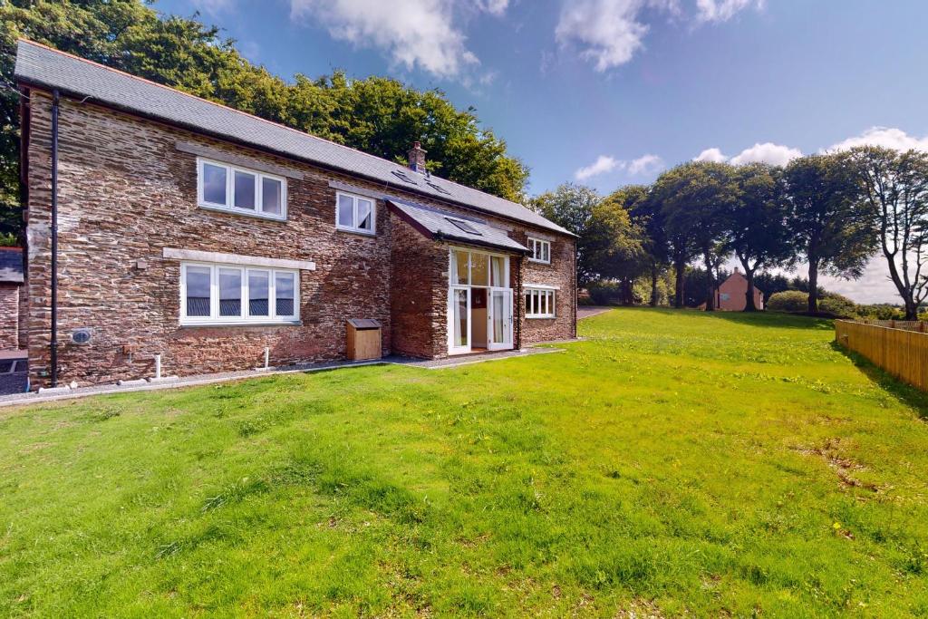 a brick house with a large yard in front of it at The Wool Barn Simonsbath in Exford