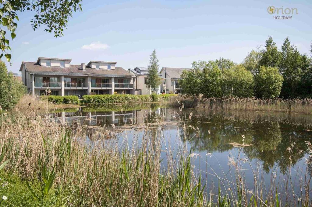 a building next to a lake in front of a building at Clearwater 82, Primrose Bank in Somerford Keynes