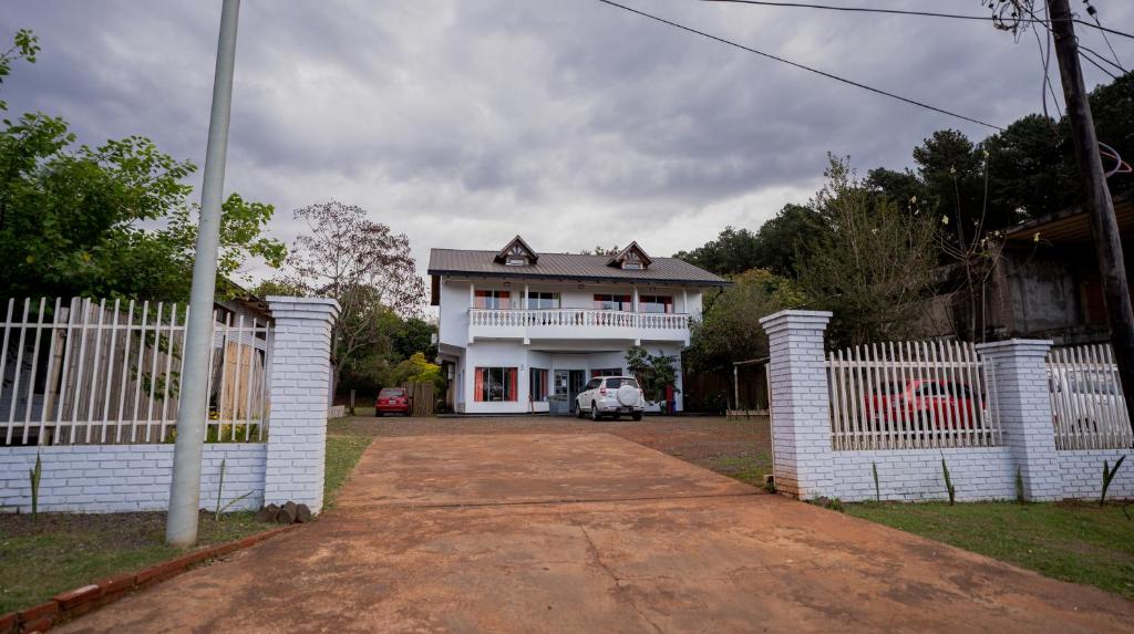 ein weißes Haus mit einem Zaun davor in der Unterkunft Hotel Puerto Libertad - Iguazú in Puerto Libertad