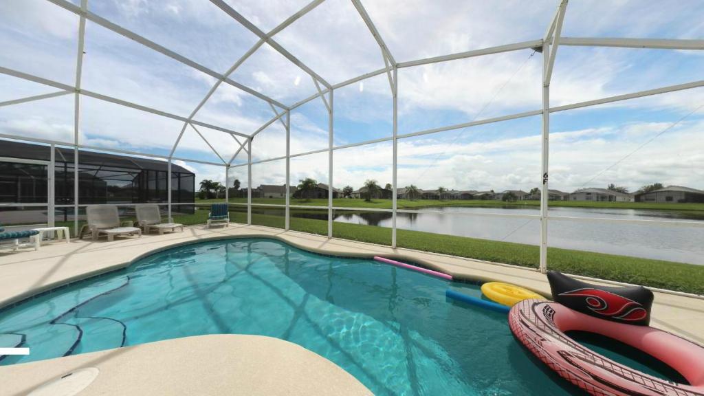 a swimming pool with a domed roof and a swimming poolvisorangering at Elite Homes - Eagle Pointe in Kissimmee