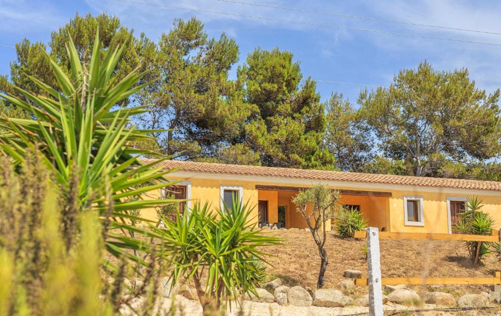 una casa amarilla con árboles delante de ella en Apartments with common swimming-pool and outdoor private area in Badesi, en Badesi