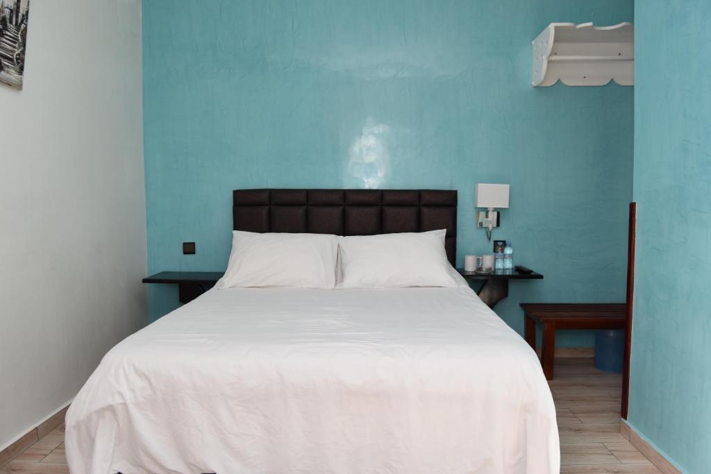 a bedroom with a large white bed with a blue wall at Hotel L'Initiale in Oualidia