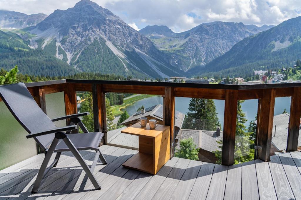 uma varanda com uma cadeira, uma mesa e montanhas em Seeblick em Arosa